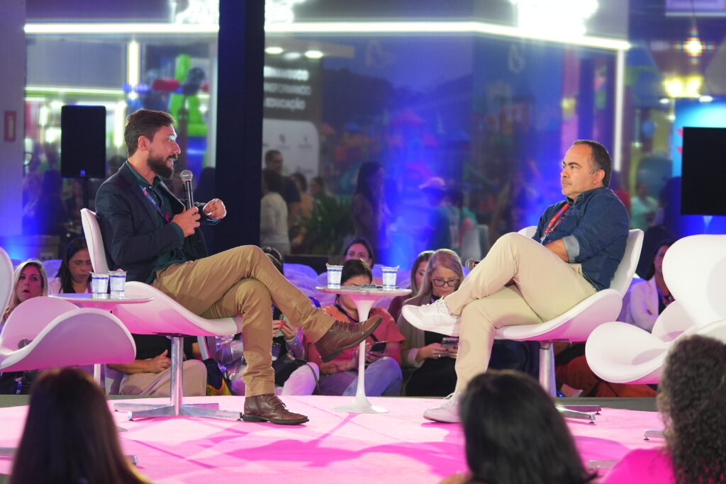 Painel de debate em palco com convidados sentados em poltronas, em evento da Escola Atlântico Avanti